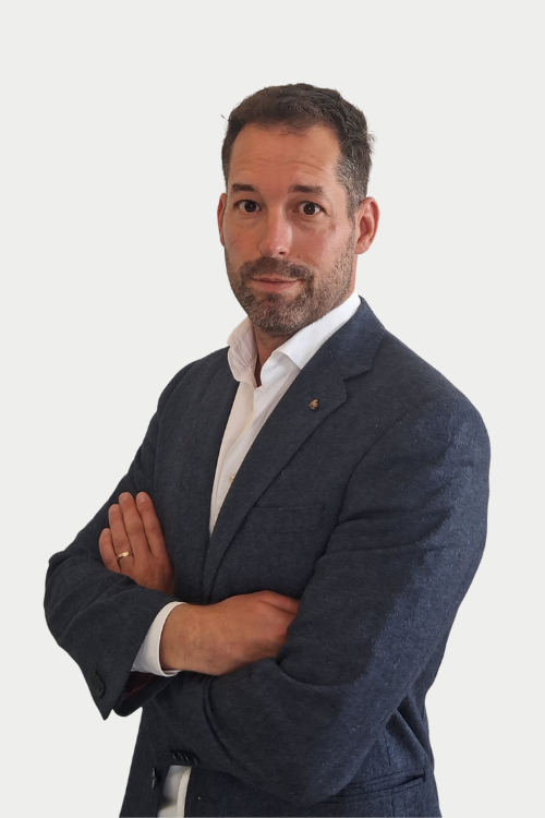 Professional portrait of a man in a navy blazer and white shirt, arms crossed, looking at the camera.